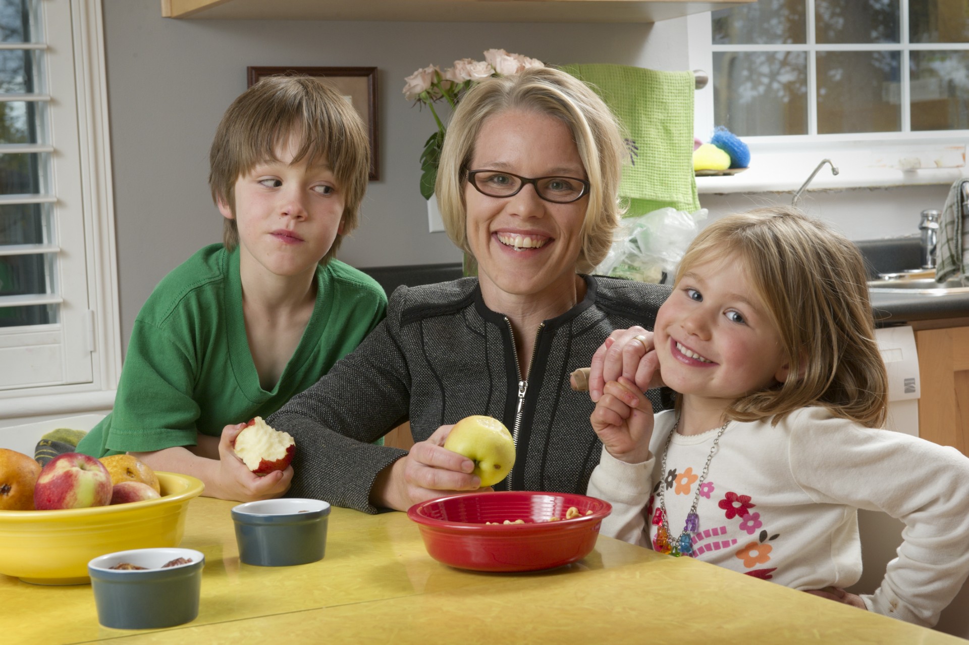 Jess Haines and two children sitting at a table together eating apples.